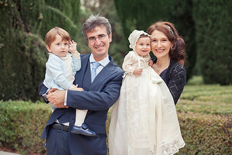 Reportaje de bautizo en exteriores, padres y dos hijos posan en los Jardines de Sabatini después de hacer el reportaje de bautizo en la Cripta de la Almudena.